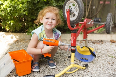 Petite fille réparant son vélo avec des outils en plastique